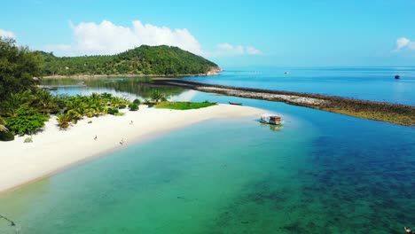 Floating-house-on-calm-clear-water-of-colorful-lagoon-near-white-sandy-beach-with-green-tropical-plants-on-vacations-island-in-Thailand