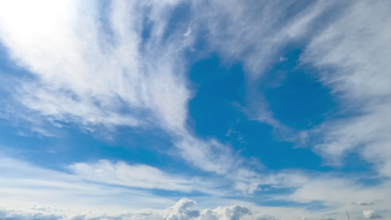 Light soft cloudscape moving along the bright blue skies. Little fluffy cumulus clouds transforming and changing the spindrift clouds. Timelapse.
