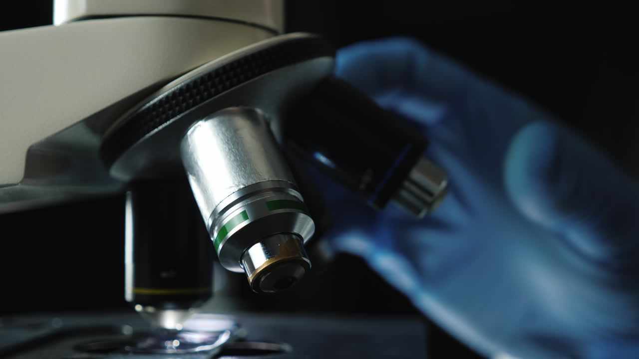 Hand in glove turns microscope lenses