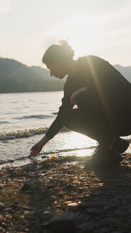 woman stroking water of lake at back sunset. attempt to relax and calm down from sadness of being alone on vacation. connecting with nature at twilight