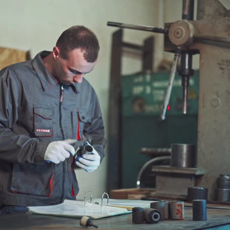 worker is measuring a produced detail by caliper.