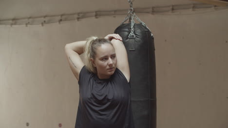 medium shot of serious woman stretching arms in gym