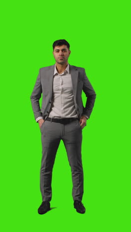 Vertical-Video-Full-Length-Shot-Of-Businessman-Standing-Against-Green-Screen-Folding-Arms-And-Putting-Hands-In-Pockets-Against-Green-Screen-1