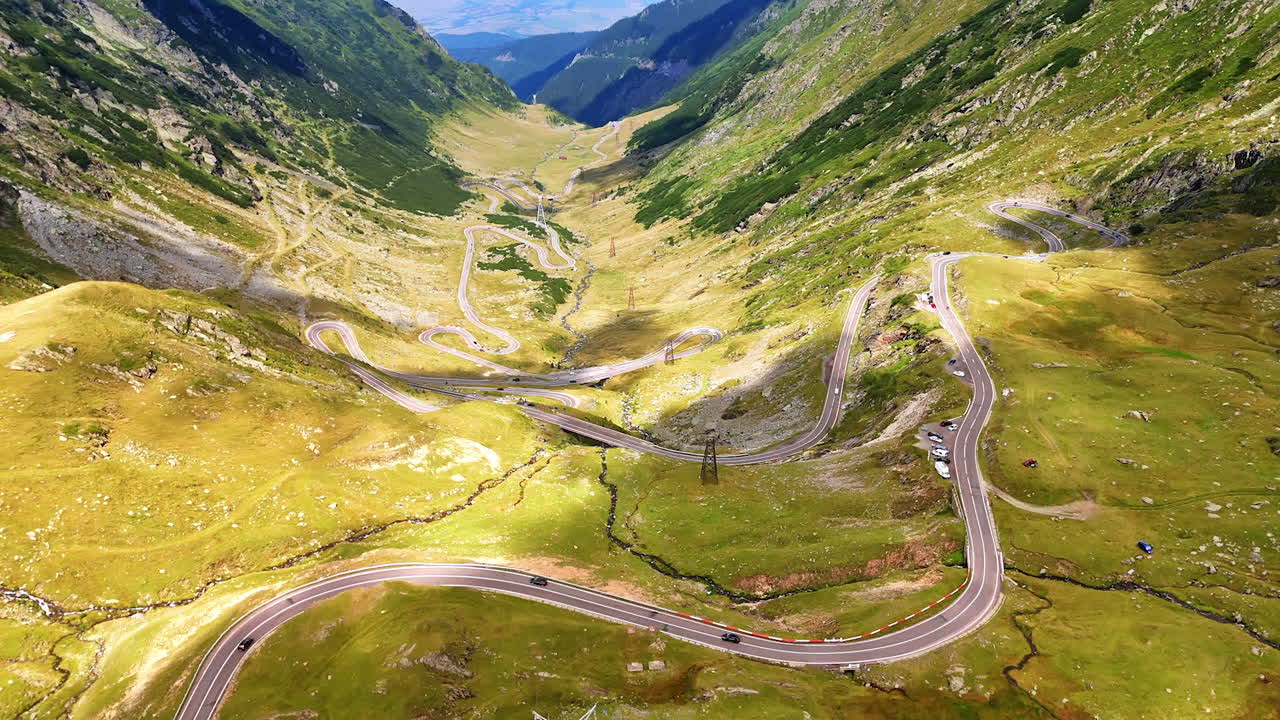 View on the famous Transfagarash highway in the Carpathian Mountains, Romania. Cars move slowly by the wriggly road. Aerial perspective