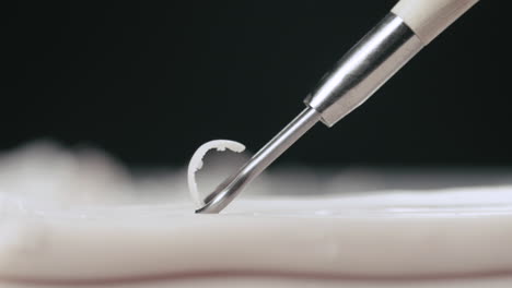 el artista usa una herramienta de cinta en un trozo de macro de plastilina