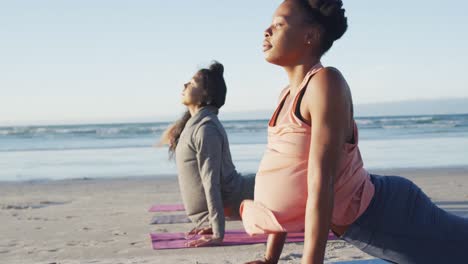 grupo de diversas amigas practicando yoga, estirándose en la playa