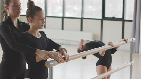 profesora corrige la posición de los brazos de la chica gimnástica en la clase de ballet