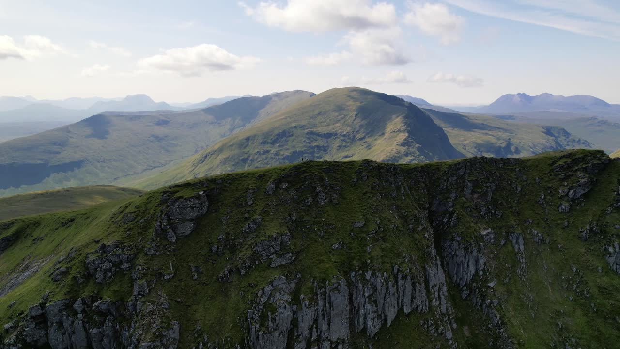 화창한 날 스코틀랜드 고원의 봉우리 사이의 녹색 산 능선 꼭대기에 서있는 남성