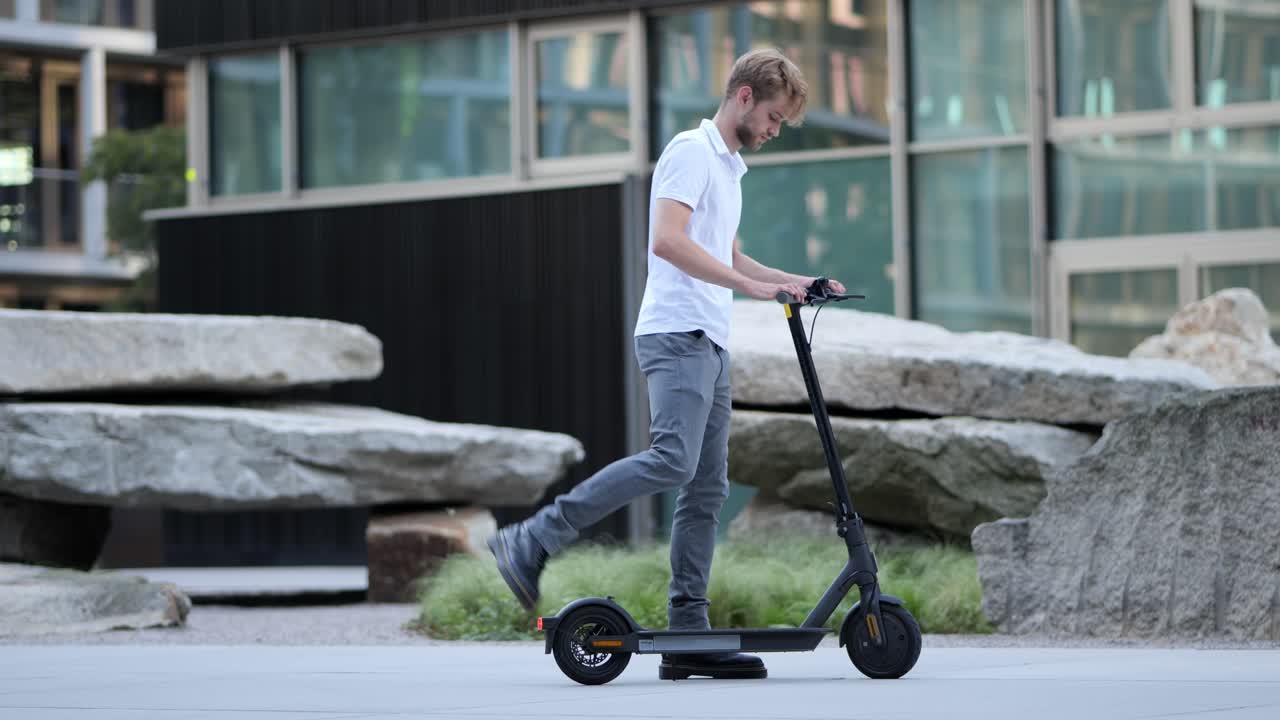 Genç bir iş adamı e-scooter'ına yürüyüp uzaklaşırken çekilen geniş çekim