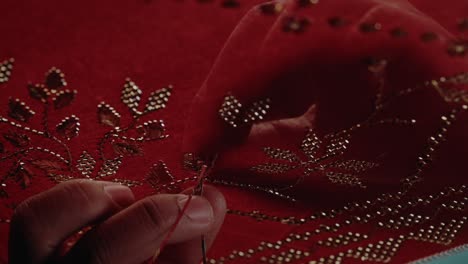 handcrafting-traditional-red-headscarf-shawl-keringkam-using-embroidery-with-gold-threads-intricately