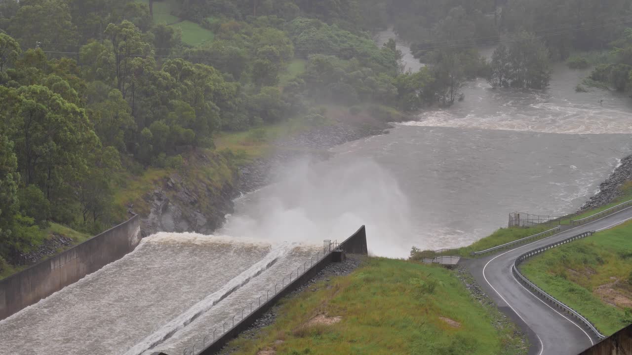 Handheld shot of Hinze Dam outflow under heavy rain and water flows during La Ni&ntilde;a, Gold Coast Hinterland, Queensland, Australia