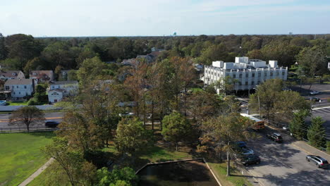 An-aerial-drone-shot-over-a-green-pond-in-a-suburban-neighborhood-on-Long-Island,-NY