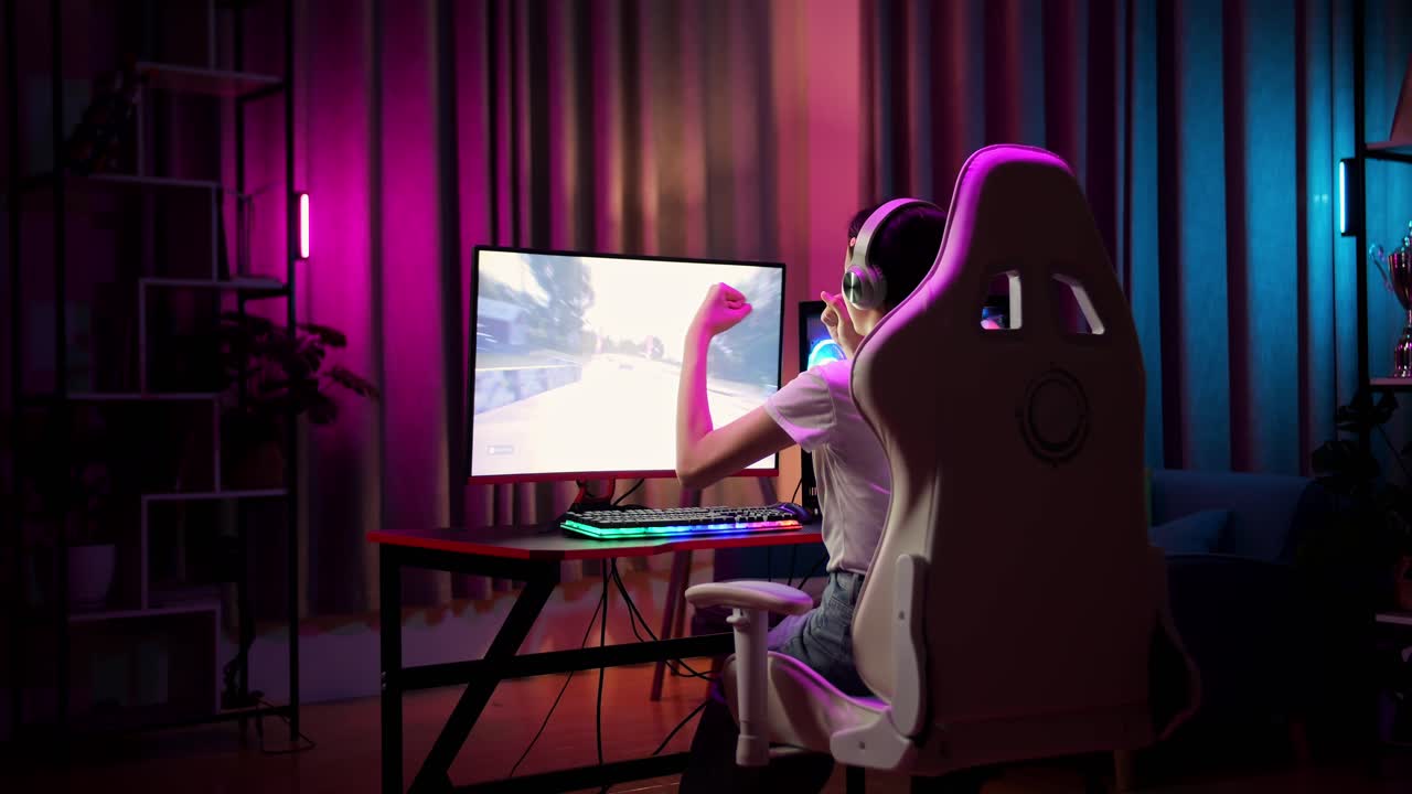 una adolescente asiática emocionada celebra la victoria mientras juega a videojuegos en la computadora, jugando a un videojuego de carreras