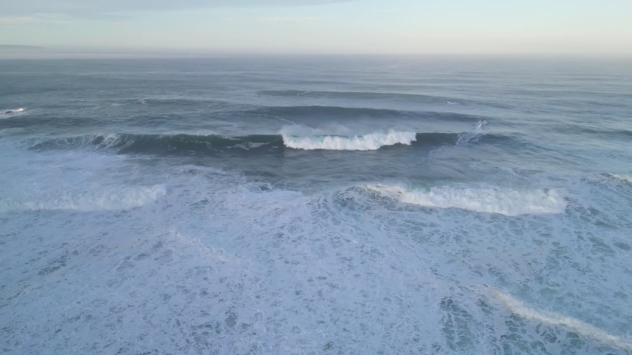 Waves crashing at Farol de Nazaré in Portugal, peaceful ocean view with vast horizon
