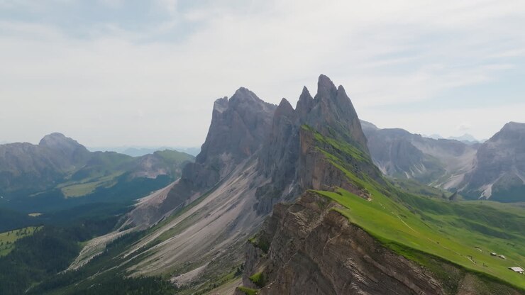 Aerial reveals jagged Seceda ridgeline and valley at golden hour in the Italian Dolomites