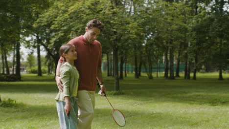 father and daughter playing badminton in the park