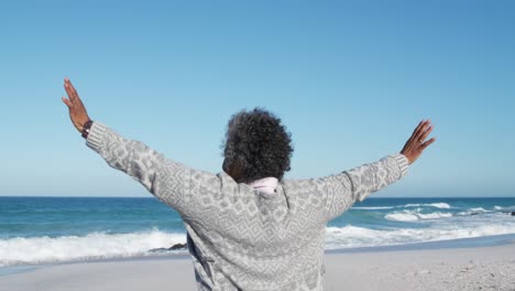 senior woman raising her arms at the beach