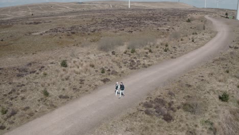 rotating aerial shot of a young couple walking through a windfarm