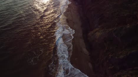 aerial 4k drone footage of over the waves off the coast of the isle of wight and then panning up to the sun setting over the sea