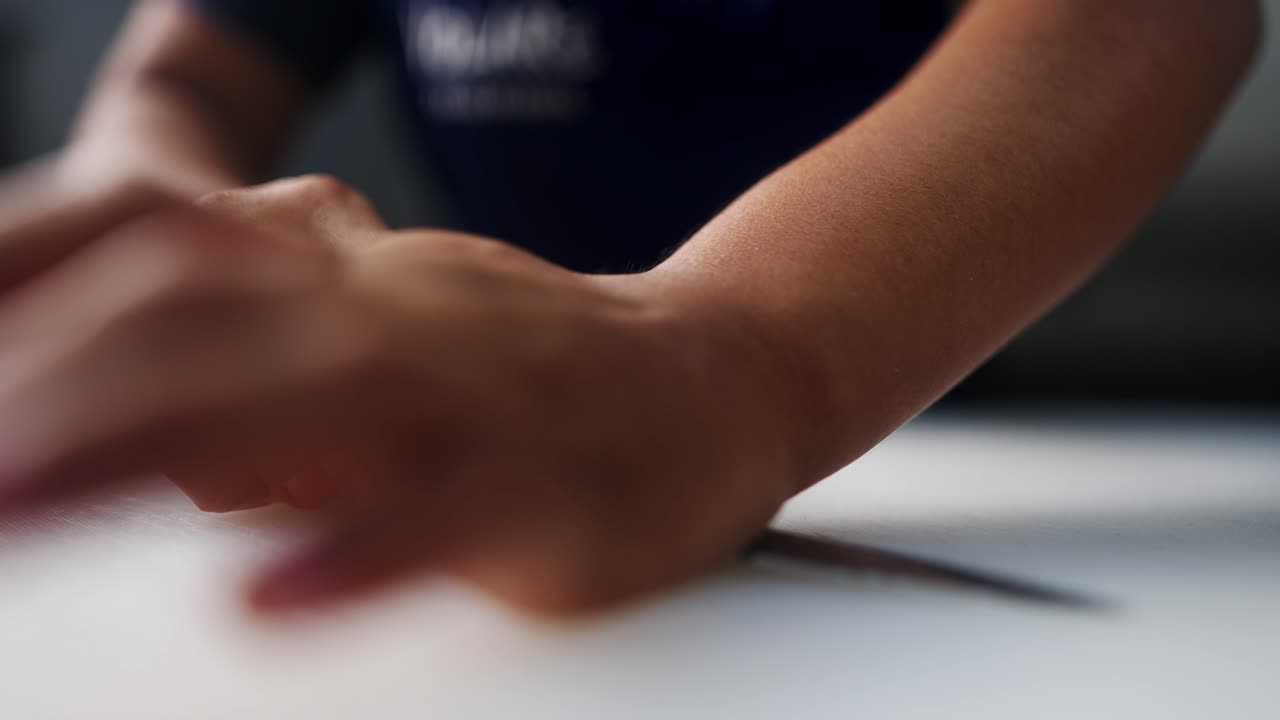 Close up view in slow motion of two hands smashing and crushing a garlic clove under a cinematic atmosphere.