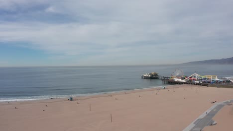 High-and-wide-panning-aerial-shot-of-Santa-Monica-beach-with-a-closed-down-pier-during-the-COVID-19-pandemic