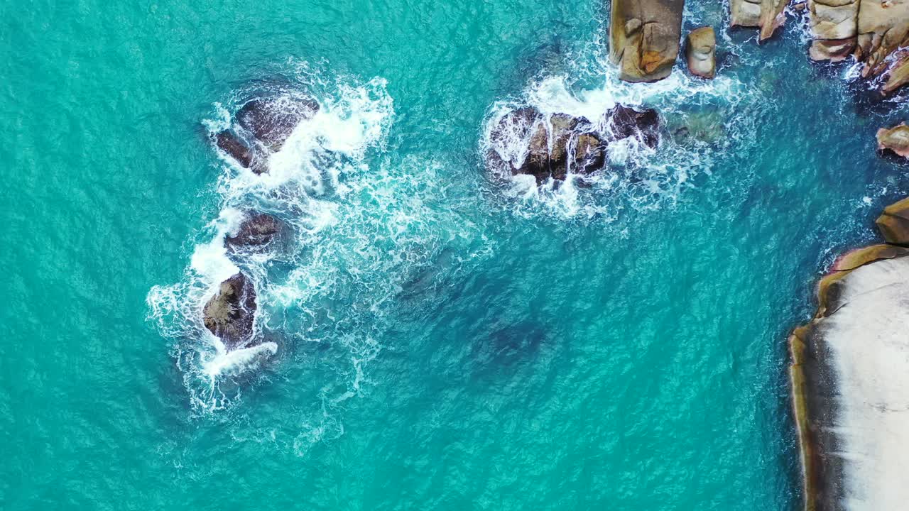 Mare turchese con onde bianche che si infrangono su scogliere calcaree sulla costa rocciosa di un'isola tropicale, Thailandia, spazio per il testo.
