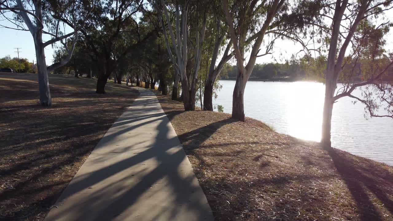 dron volando sobre un sendero peatonal a baja altitud cerca de un parque fluvial