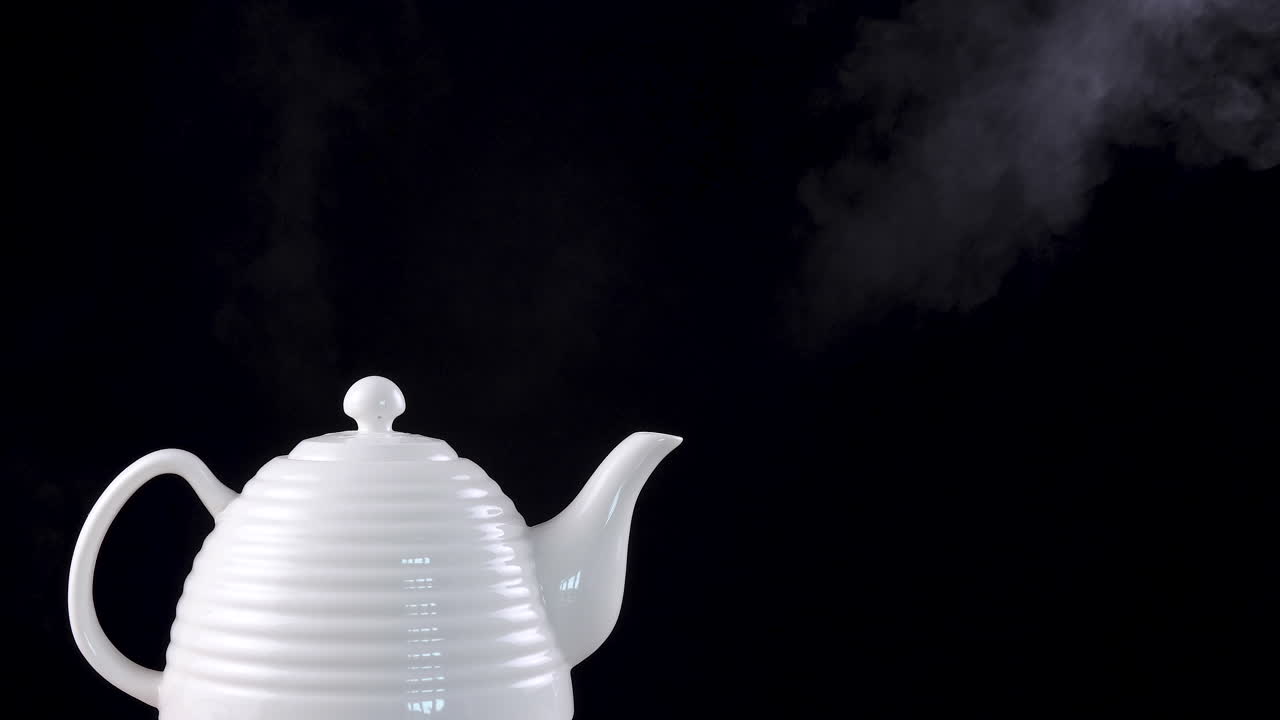 Tea pot on black background with boiling water