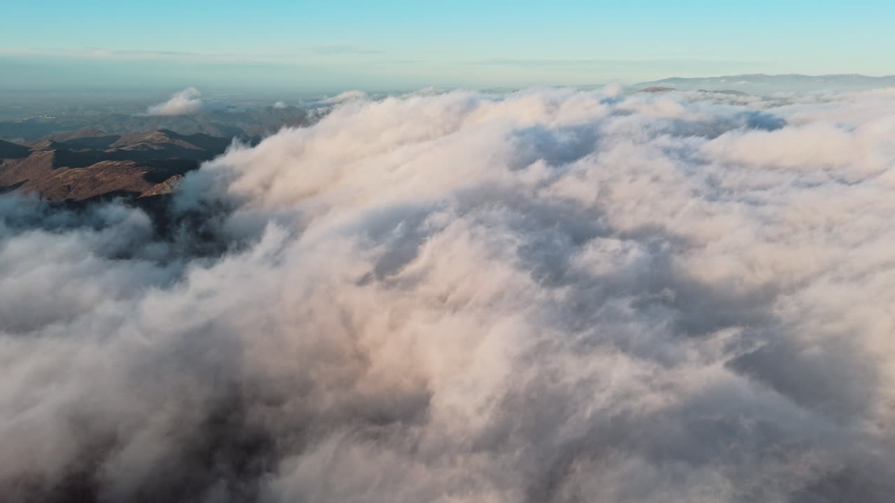 Le nuvole si muovono sulle montagne all'alba, creando una serena scena naturale.