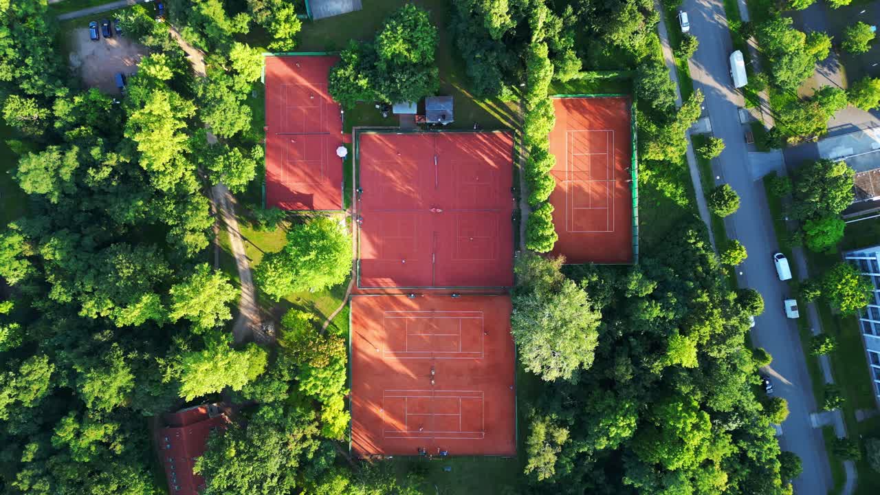 several tennis courts nestled within a dense forest, providing a tranquil escape in the heart of the city Berlin. Unbelievable aerial view flight drone camera pointing down