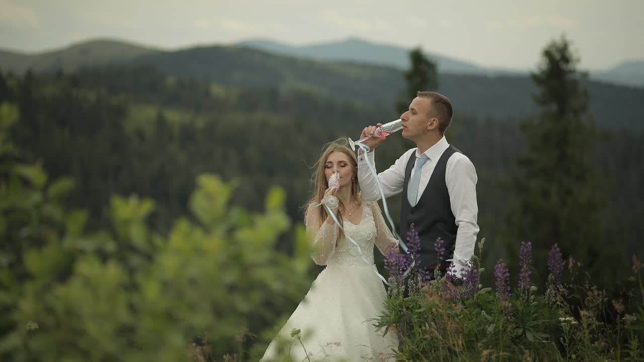 Gom og brud drikker champagne på bjergskråninger. Brudepar. Familie.