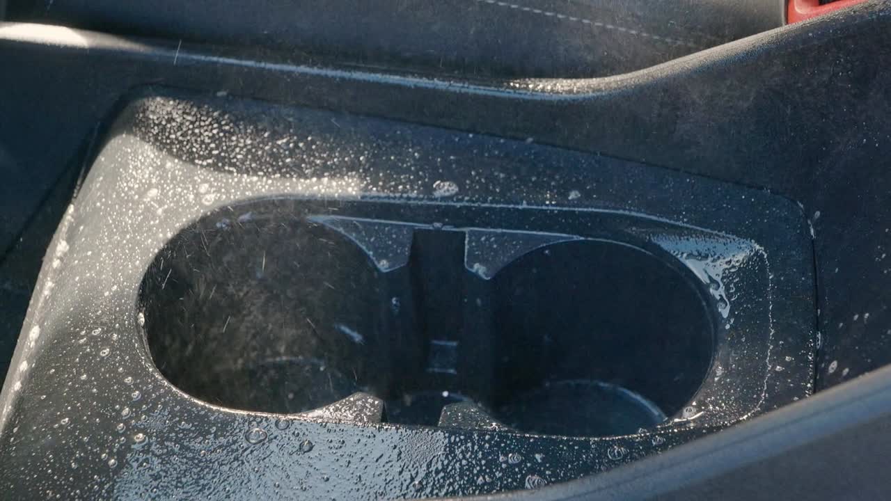 Spraying cleaning solution into drity car suv cup holder and surrounding plastic - close up