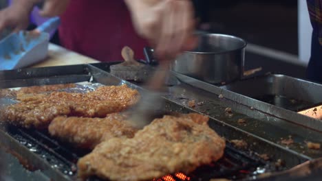 mouthwatering delicious honey soy coated fried chicken fillet grilling on hot grill, professional chef brush tasty sauce on the meat with aromatic smell at famous night market, taiwan, asia