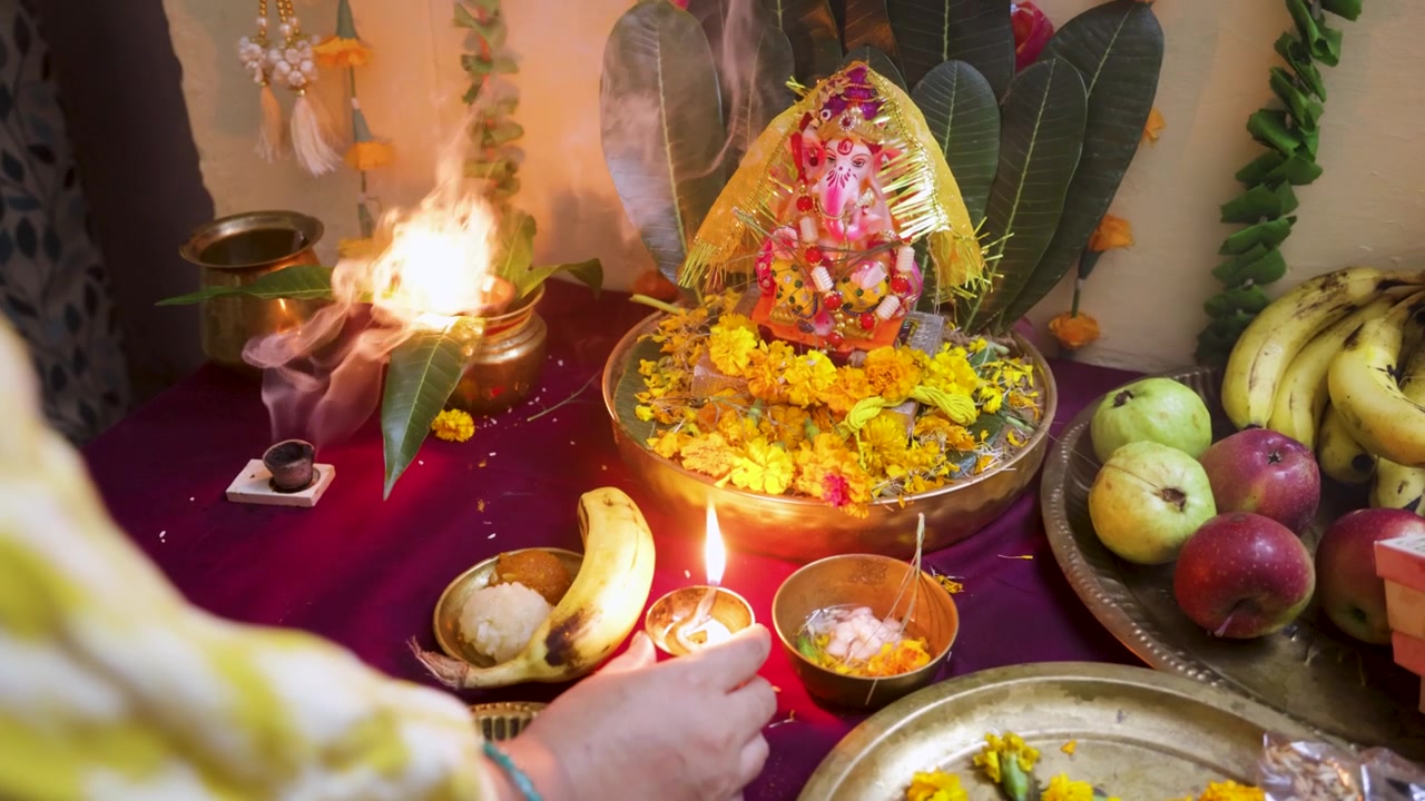 Donna che esegue l'aarti durante la cerimonia di culto del Signore Ganesha a casa