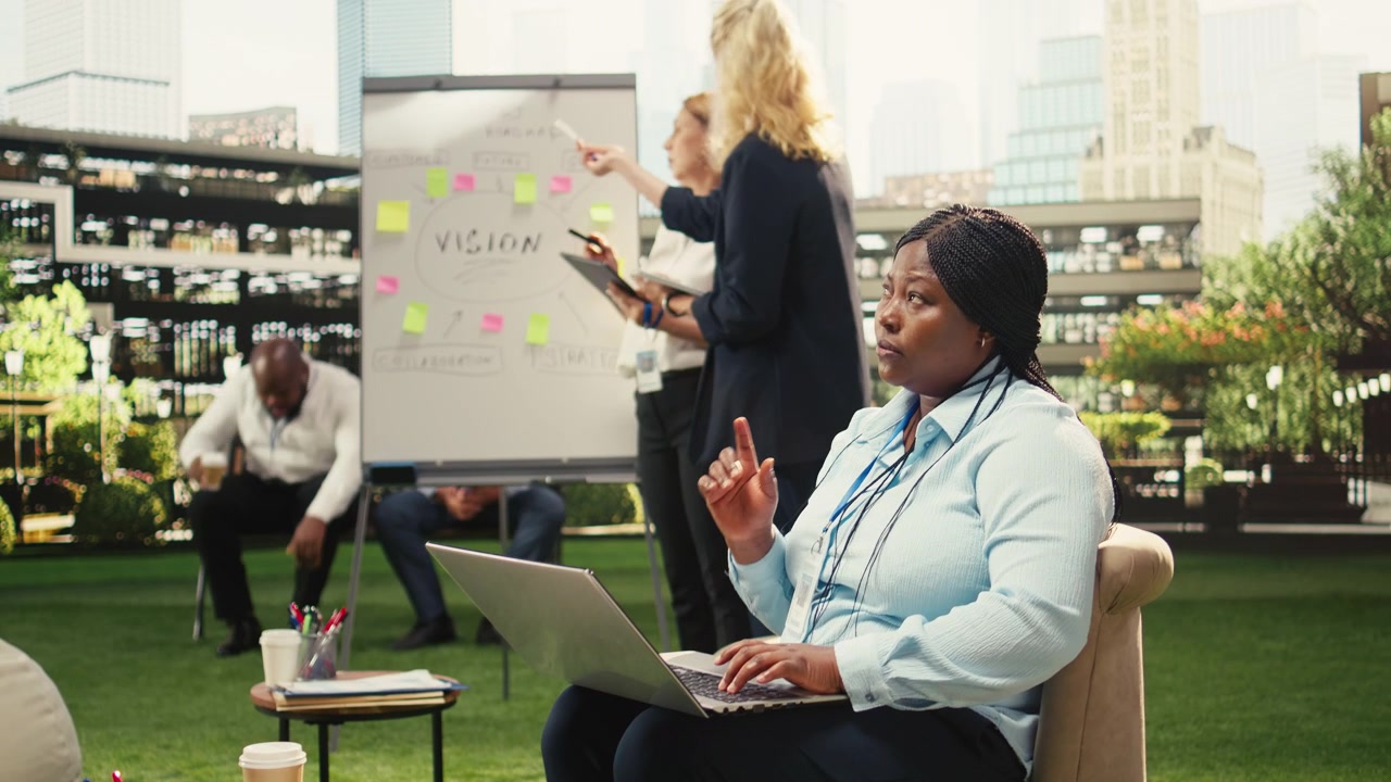 Businesswoman Working on Laptop During Team Meeting on Office Rooftop