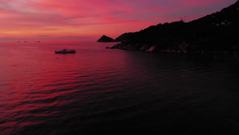 Aerial-shot-of-Koh-Tao-island,-colourful-sunset-at-the-beach-with-many-boats-floating,-Thailand