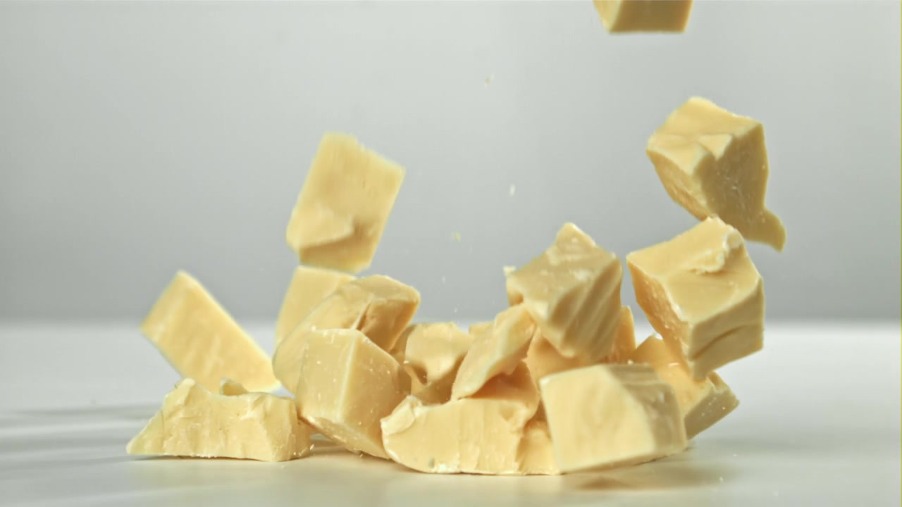 Morceaux de chocolat blanc tombant au ralenti sur fond blanc