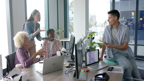 discussing project, diverse team using laptops and vr headsets in office