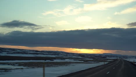 Roadtrip-Bei-Sonnenuntergang-Durch-Die-Verschneite-Isländische-Landschaft-Aus-Der-Sicht-Des-Fahrers,-Wolken-Bemalen-Den-Himmel