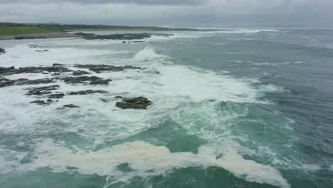 vista aérea, 4k, siguiendo las olas rompiendo en las rocas