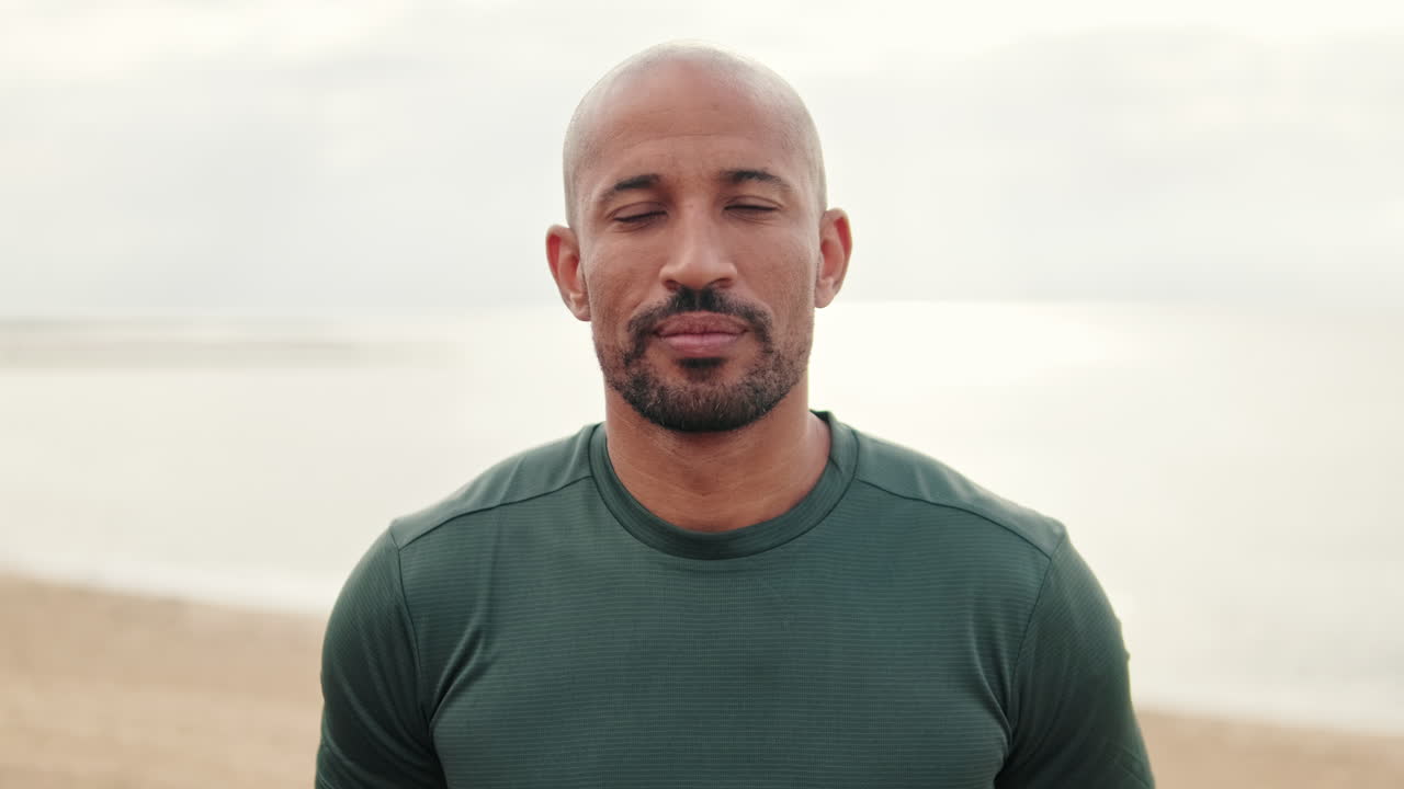 Bald Bearded Man Standing on Beach Looking at Camera