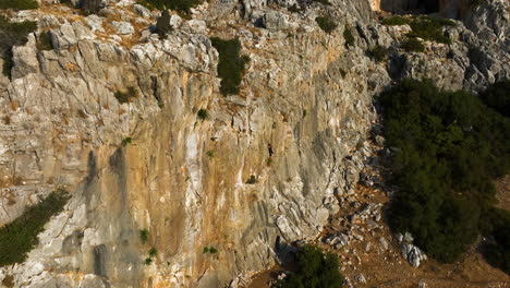 drone orbiting a mountain climber rope climbing a large rocky cliff, golden hour