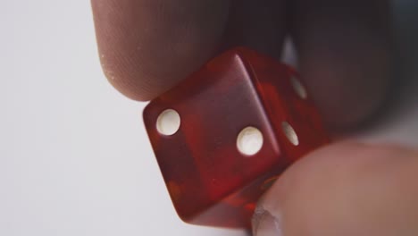 man shows bright red dice with spots on light background