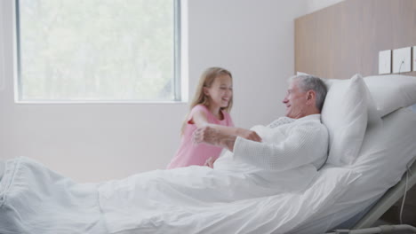 Portrait-Of-Girl-Lying-In-Bed-In-Hospital-Ward-Hugging-Teddy-Bear