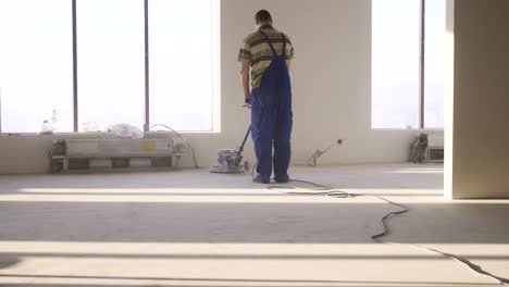 trabajador pulindo el piso de hormigón en un edificio de oficinas