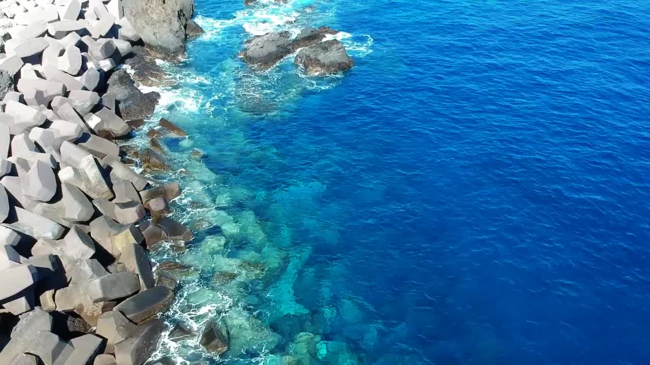 Aeriel drone footage at Garachico - Caleton (Tenerife) next to the blue ocean as the waves hit the rocks in the water