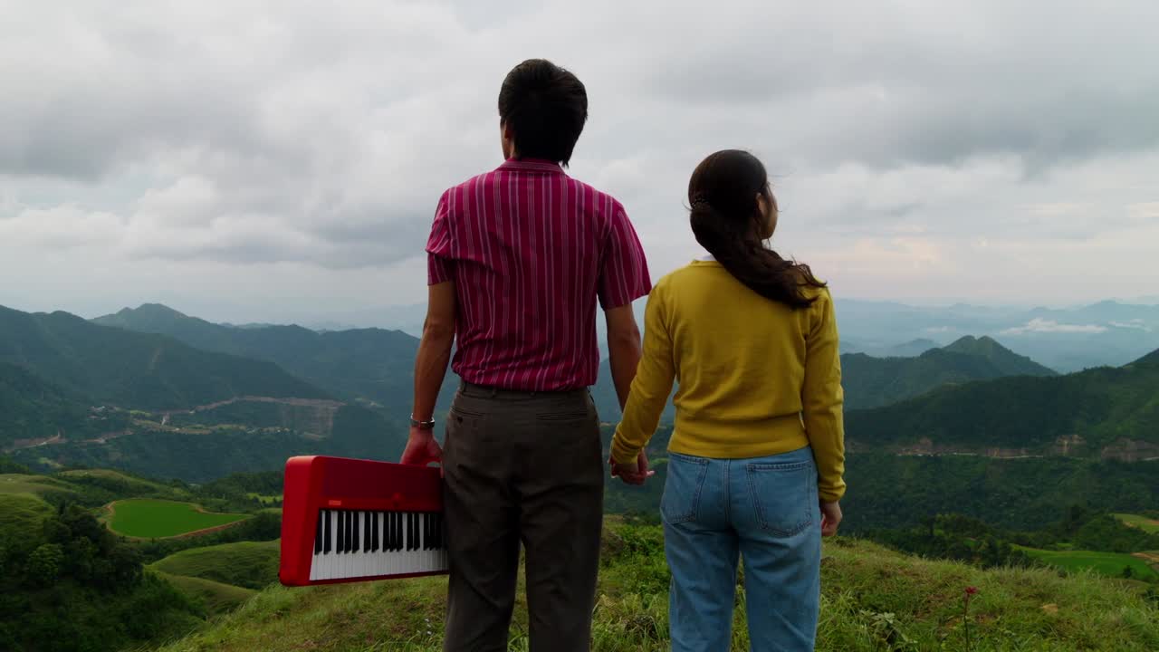 Two musicians embrace the breathtaking Hajan rice terraces, holding a keyboard under a cloudy sky. The mood is serene, capturing a harmonious blend of nature and music