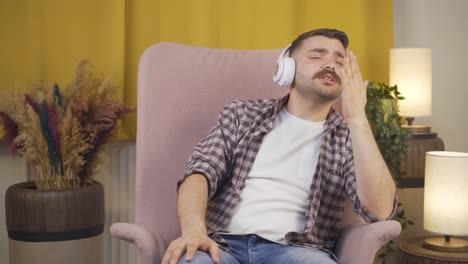 man listening to music with headphones is unhappy and sad.