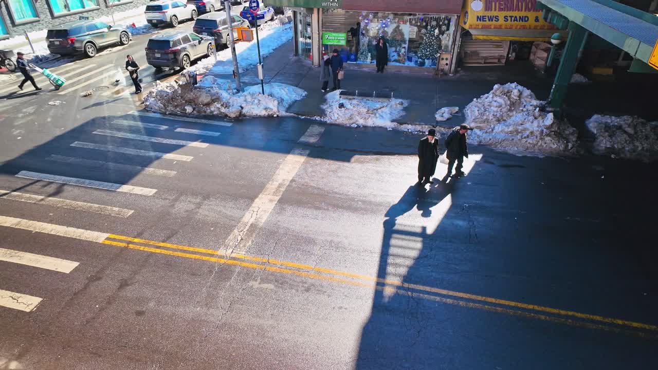 New York, USA, 25 dicembre 2025: Pedoni che attraversano una strada cittadina soleggiata dall'alto. Vista elevata di persone che camminano attraverso un incrocio innevato in un quartiere di New York City.