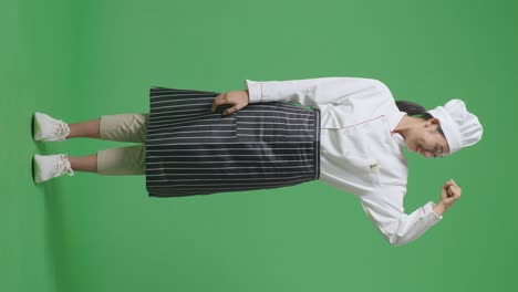 full body of asian woman chef smiling and flexing her bicep while standing in the green screen background studio